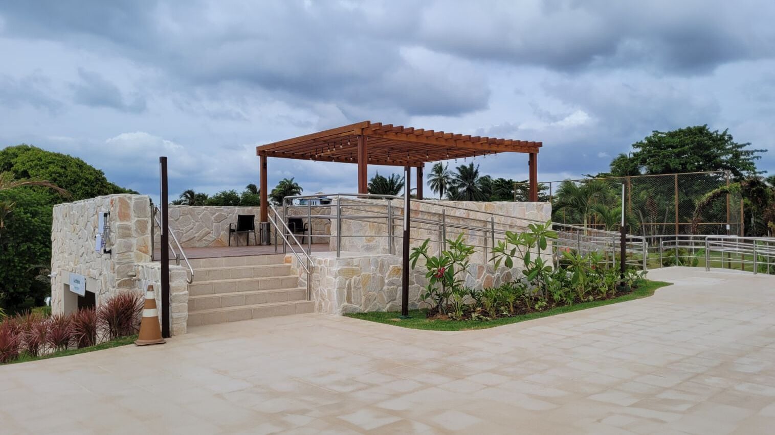 A stone building with a wooden pergola and a staircase leading to a covered area.