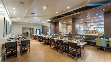 Un restaurant spacieux doté de plusieurs espaces de restauration, d’un plancher en bois et d’un design moderne au niveau du plafond.