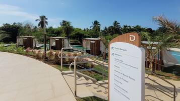 A sign with directions to various amenities including a bungalow area, restrooms, children's playground, beach tennis courts, soccer field, pet area, and walking track.