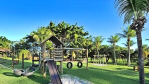 A playground with a wooden swing set, tire swings, and a slide. - Hotel Deville Prime Salvador (Salvador)