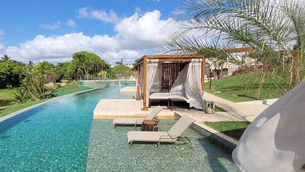 A pool with clear water, surrounded by greenery and a gazebo with white curtains. - Hotel Deville Prime Salvador (Salvador)