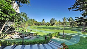 A golf course with a well-maintained green, a stone pathway, and palm trees. - Hotel Deville Prime Salvador (Salvador)