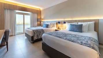 Quarto de hotel com duas camas, uma escrivaninha e vista para a cidade.