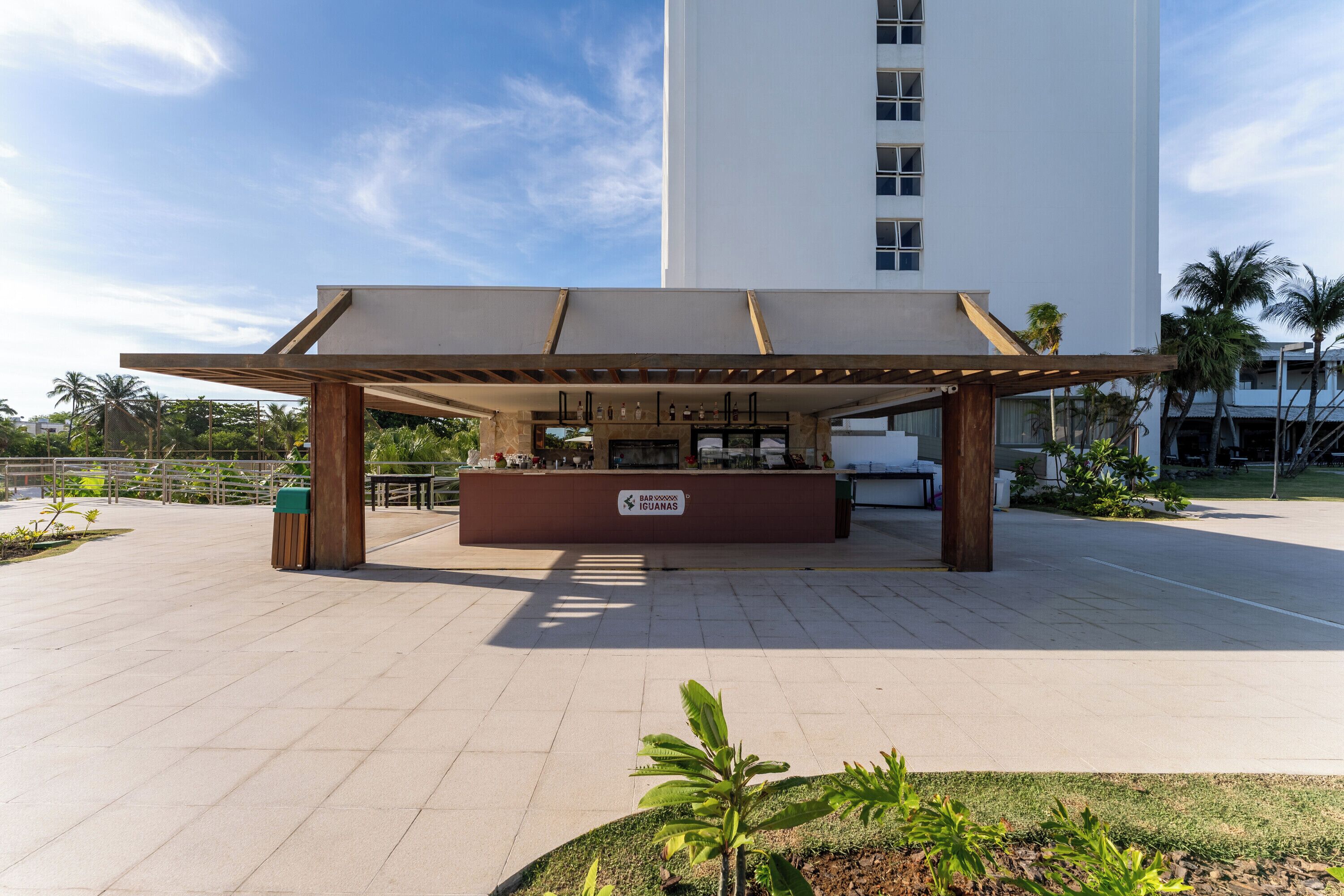 Uma área de bar ao ar livre coberta, com uma placa indicando que é um bar em Iguanas.