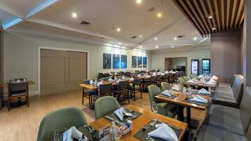 Un comedor de hotel con varias mesas, sillas y una zona de bar.