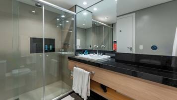 A modern bathroom with a glass shower enclosure, a vanity with a black countertop, and a large mirror above the sink.