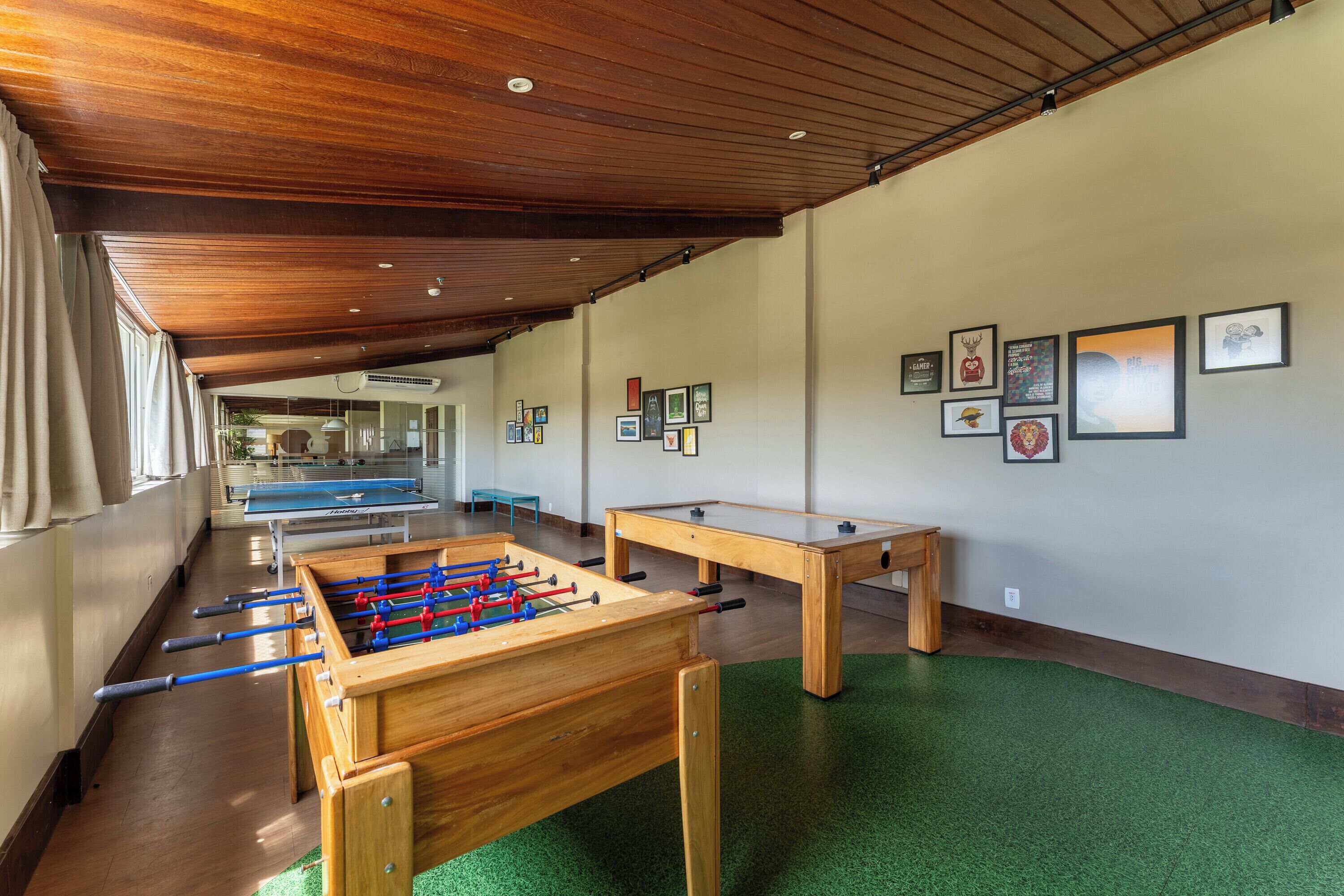 Una habitació amb taula de futbolí, taula de bitlles i taula de ping-pong.