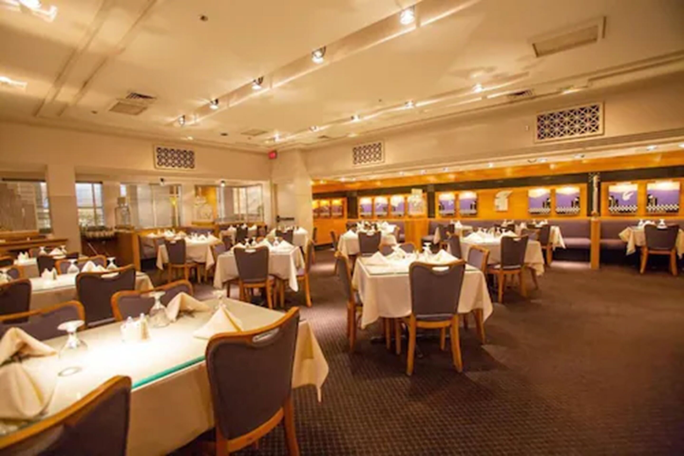 A spacious dining area with multiple tables and chairs, arranged in a banquet style.
