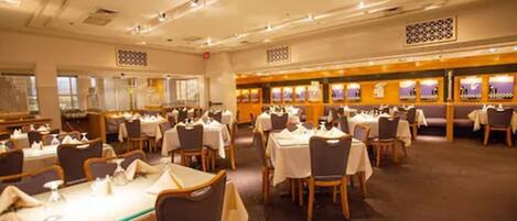 A spacious dining area with multiple tables and chairs, arranged in a banquet style.