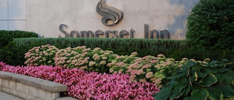 A sign for Somerset Inn with a logo, surrounded by well-maintained hedges and flowering plants.