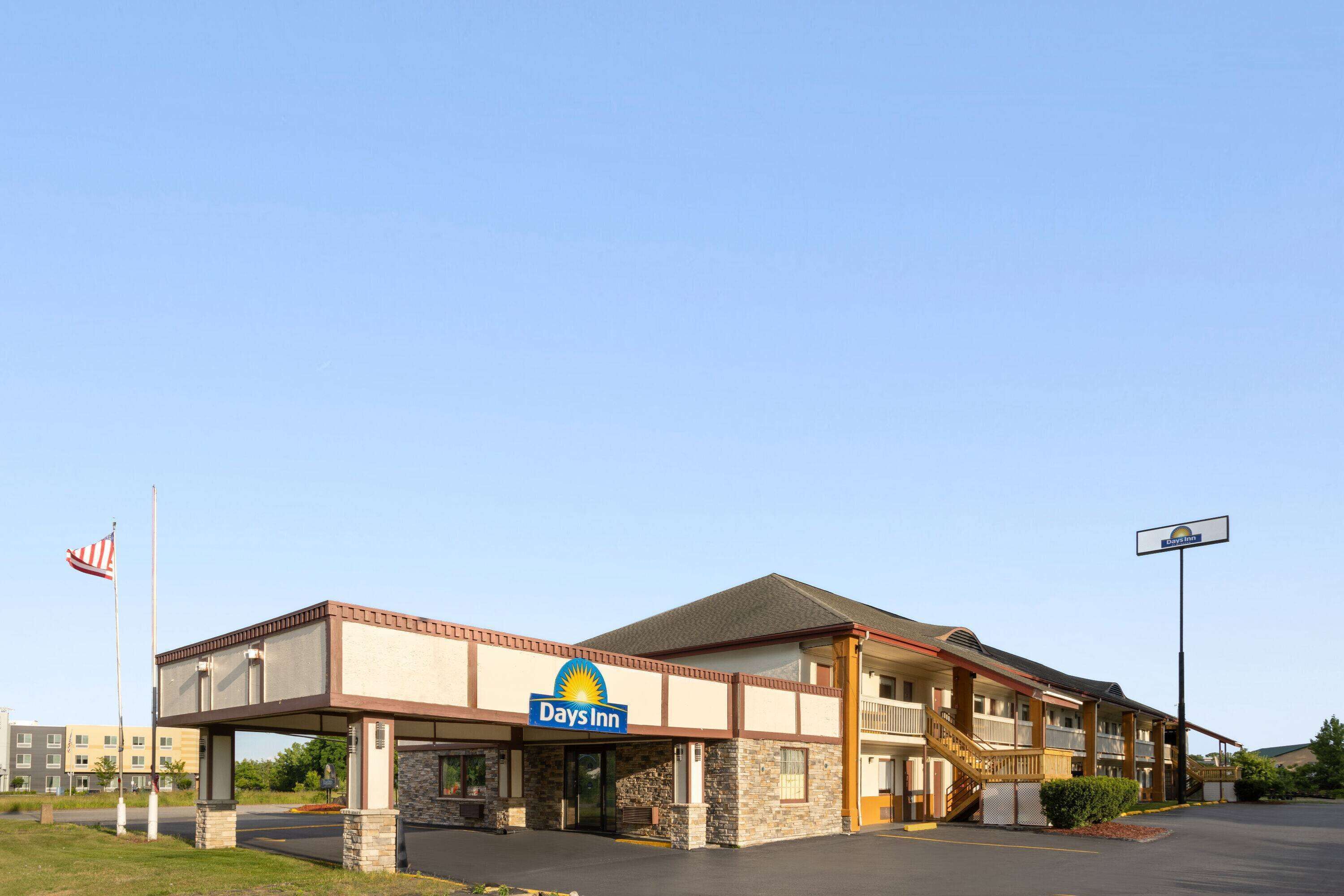 A Days Inn with a two-story structure, a covered entrance, and a flagpole with an American flag.