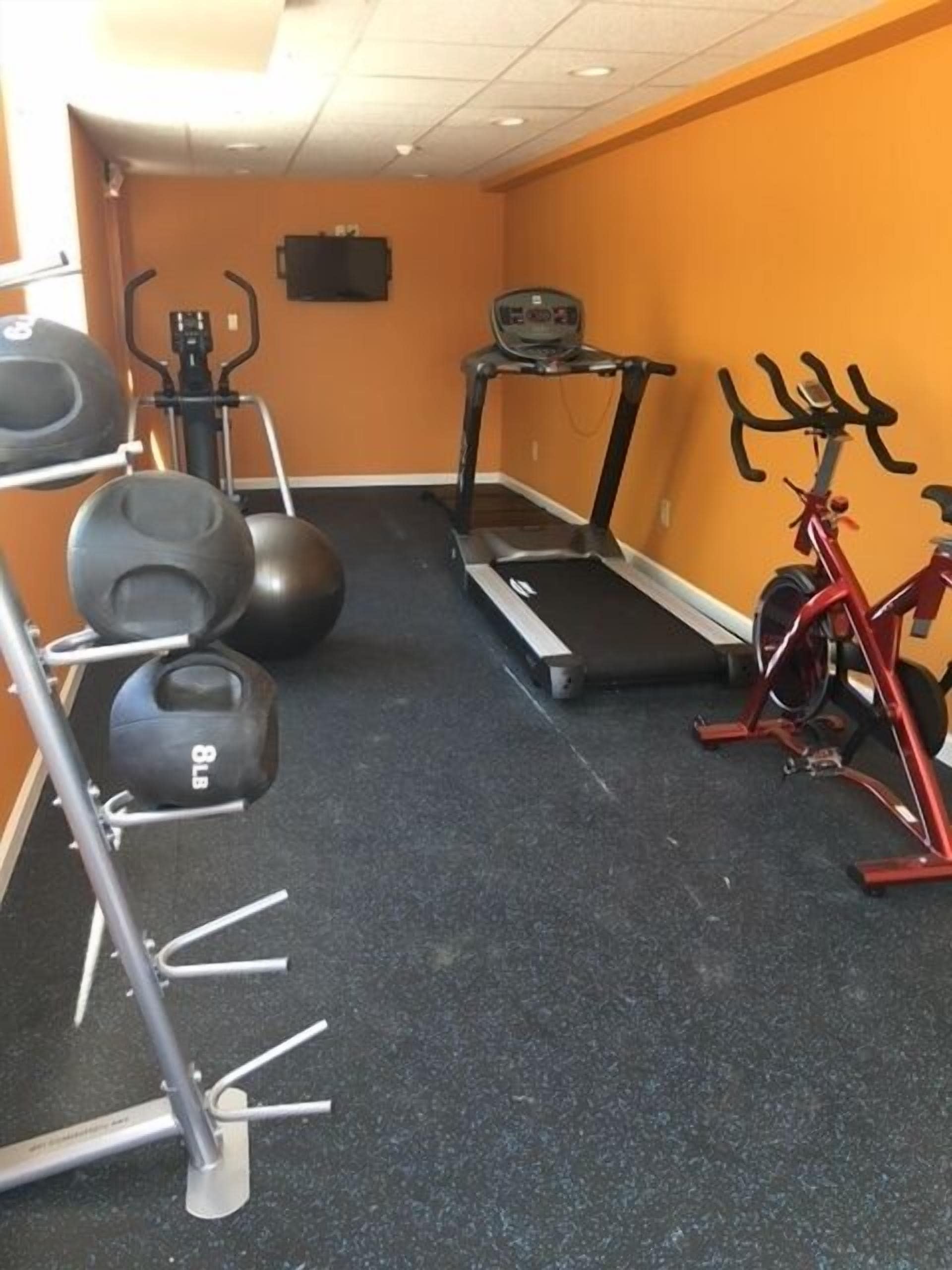 Un gimnasio con equipo de ejercicio, incluyendo una cinta de correr, elíptica y bicicleta estática.