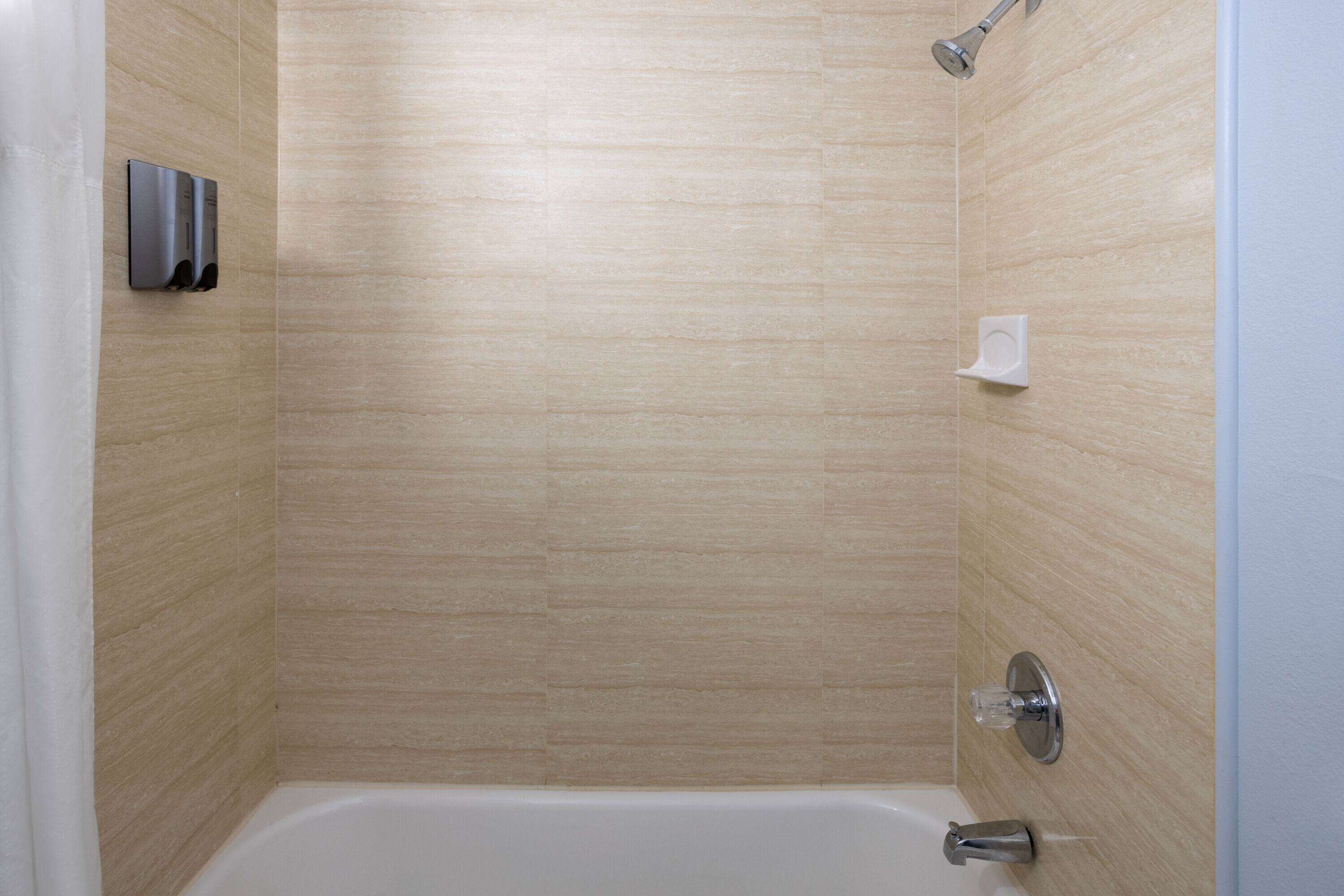 Un baño moderno con una bañera, un cabezal de ducha y un secador de manos.