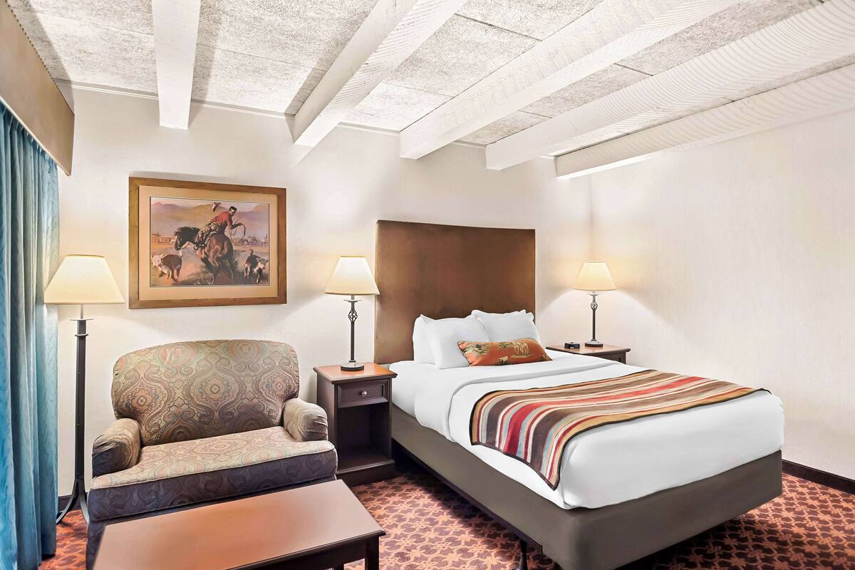 A hotel room with a large bed, a sofa, a desk, and two bedside lamps.