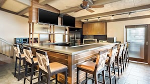Una cocina moderna con una isla central, taburetes de bar, electrodomésticos integrados y un ventilador de techo.
