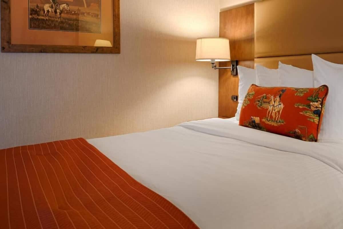 Ein Hotelzimmer mit einem Bett, einer Wandlampe und einem gerahmten Bild.