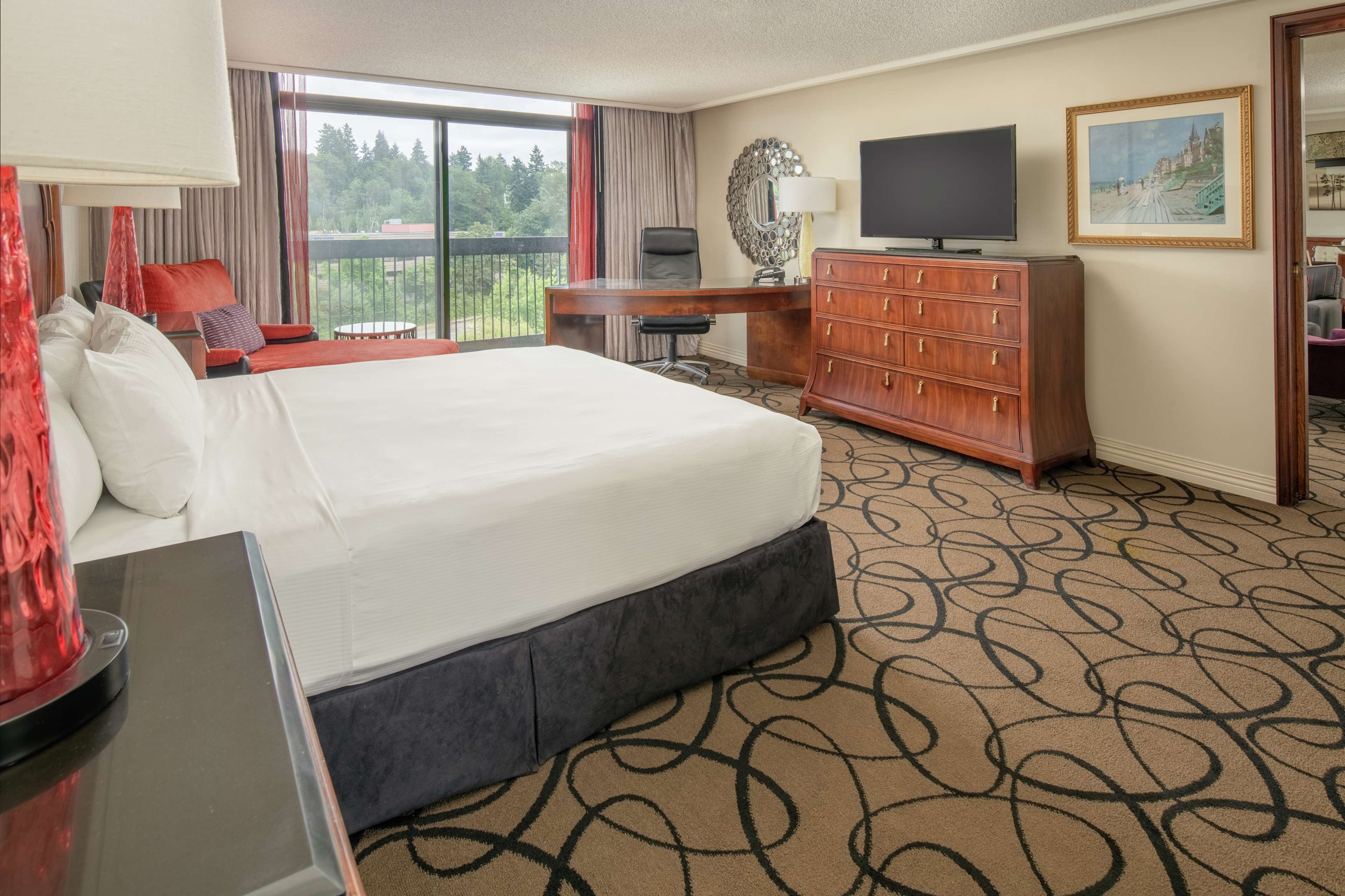 Une chambre d’hôtel avec un grand lit, un bureau, une télévision et une vue sur l’extérieur.
