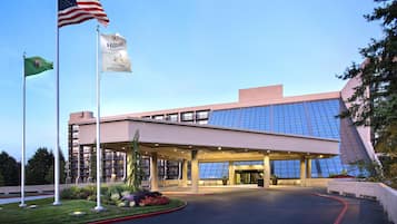 A modern building with a glass facade, a flagpole with the American flag, and a flag with 'Hilton Hotels & Resorts' branding.