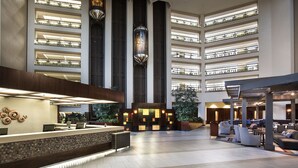 A spacious lobby with a reception desk, seating area, and multiple floors with large windows. - Hilton Bellevue (Bellevue)