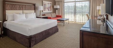 A hotel room with a large bed, a desk, a sofa, and a TV.
