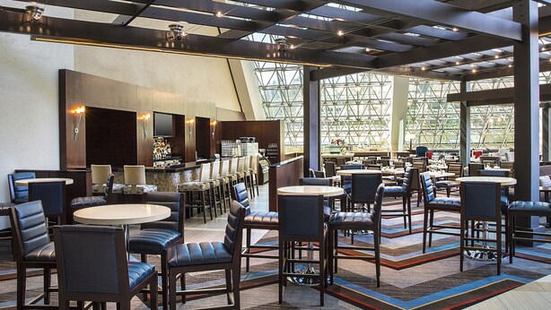 A spacious indoor area with a high ceiling and a geometric glass structure. There are multiple seating areas with tables and chairs. - Hilton Bellevue (Bellevue)