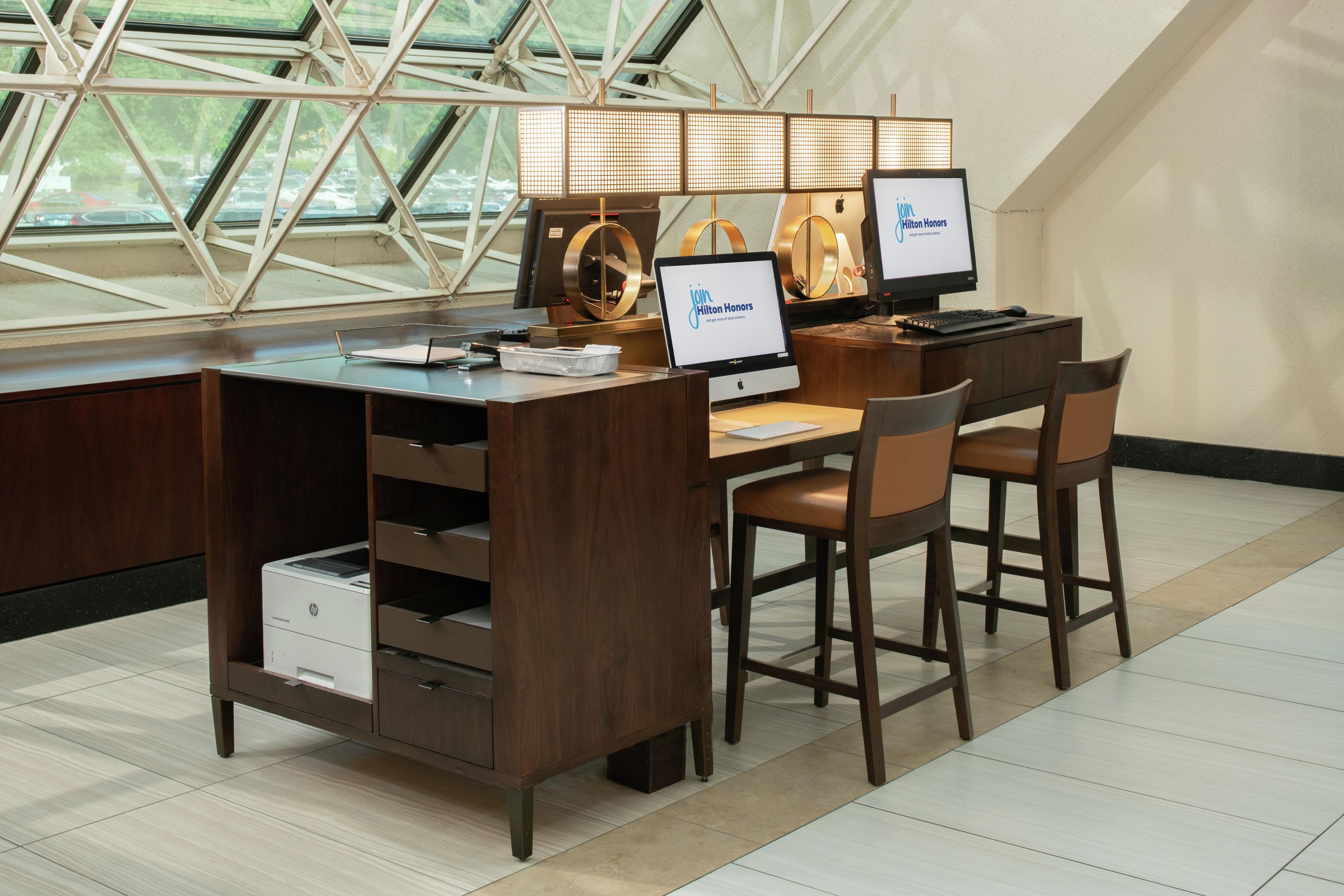 A modern hotel workspace with two desks, chairs, and a large window with a geometric view.