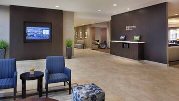A modern lobby with seating, a digital display, and a 'Boarding Pass' sign.