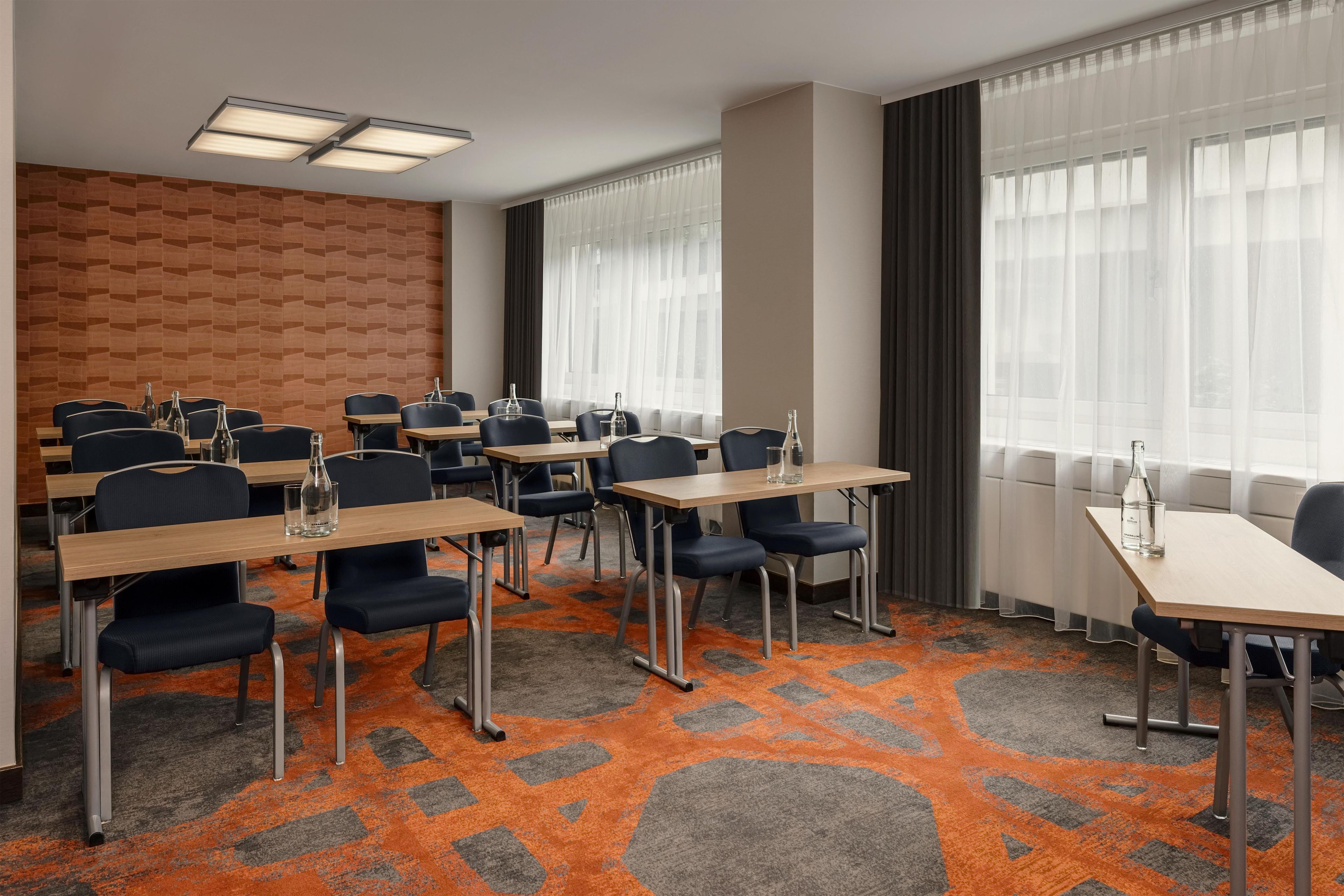 A conference room with tables, chairs, and a patterned carpet.