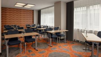 A conference room with tables, chairs, and a patterned carpet.