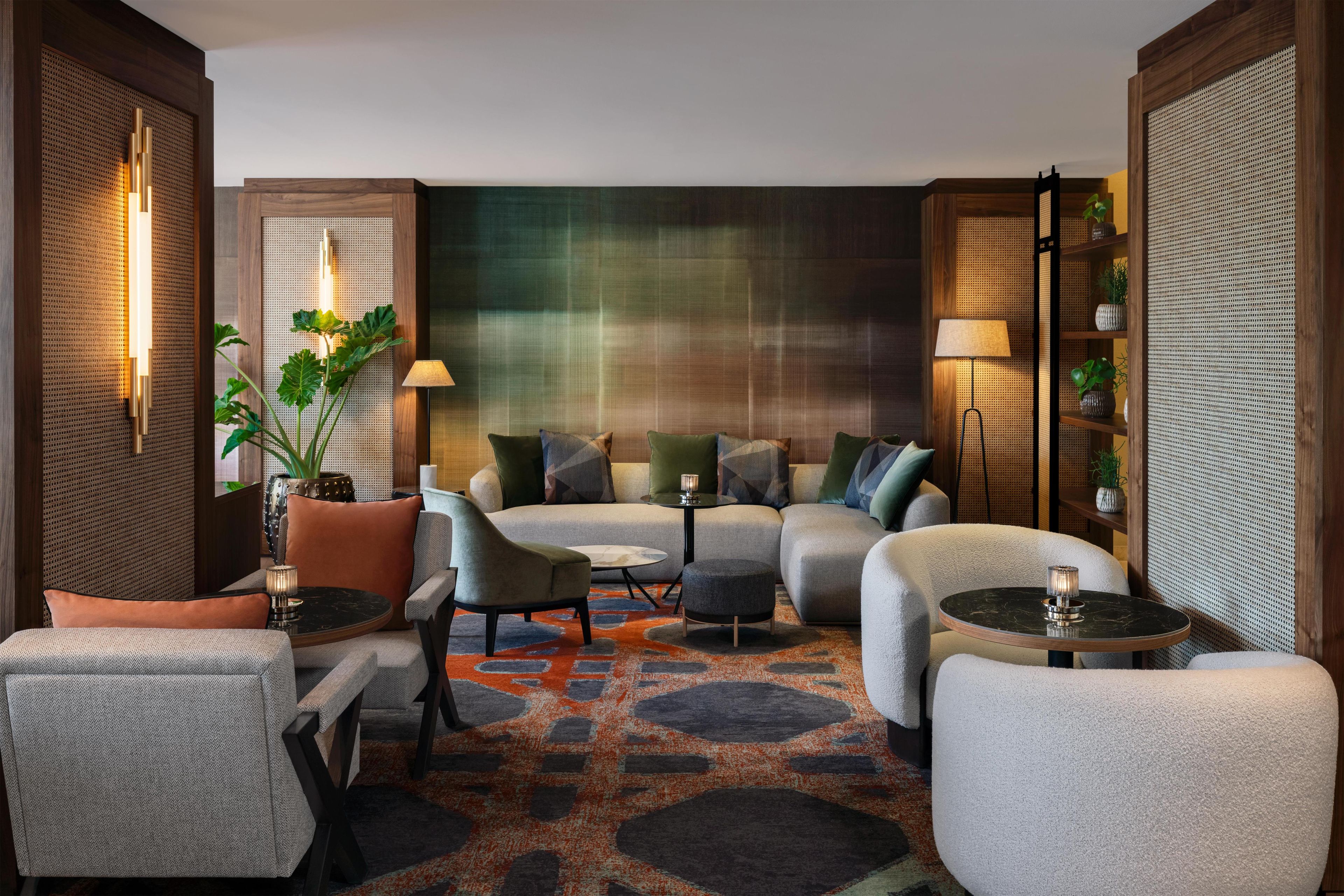 A modern living room with a sofa set, armchairs, a coffee table, and a patterned rug.