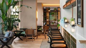 A modern interior with a long bar, seating area, and potted plants.