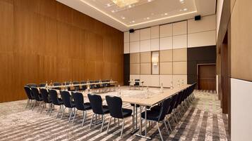 A conference room with a long table, chairs, and a carpeted floor.