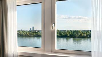 Een kamer met een groot raam met uitzicht op een waterpartij en een stadsgezicht.