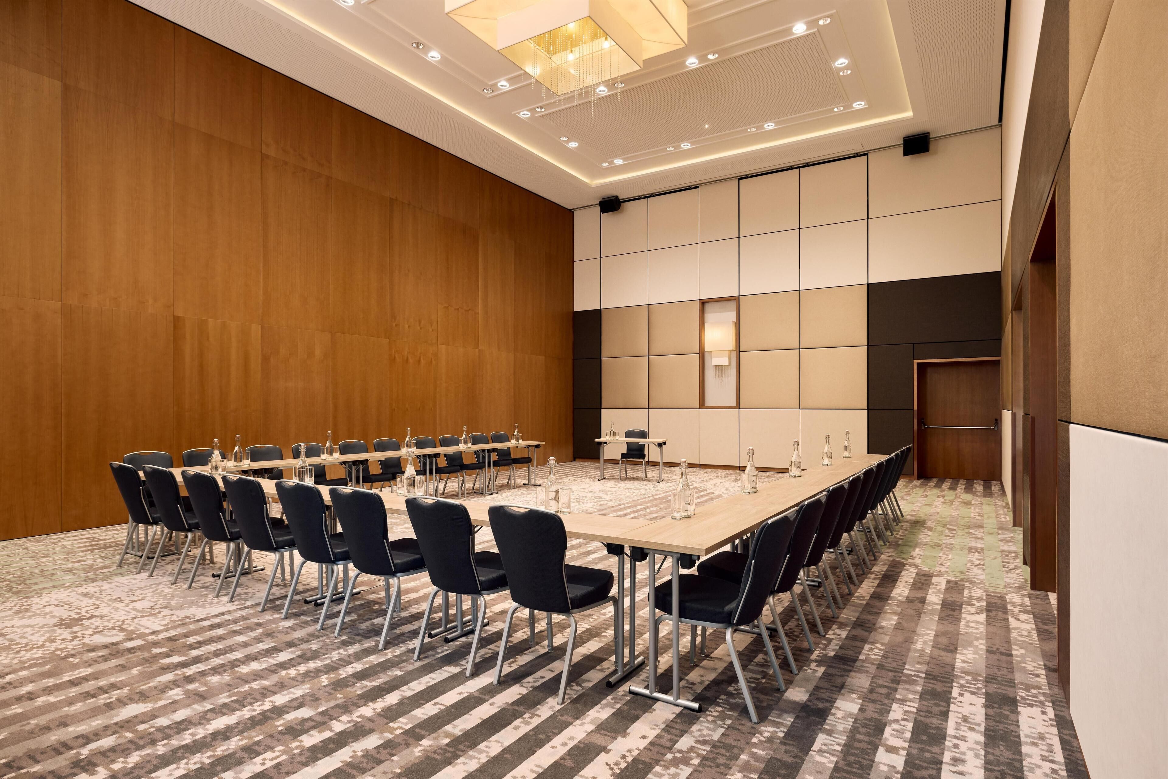 A conference room with a long table, chairs, and a patterned carpet.