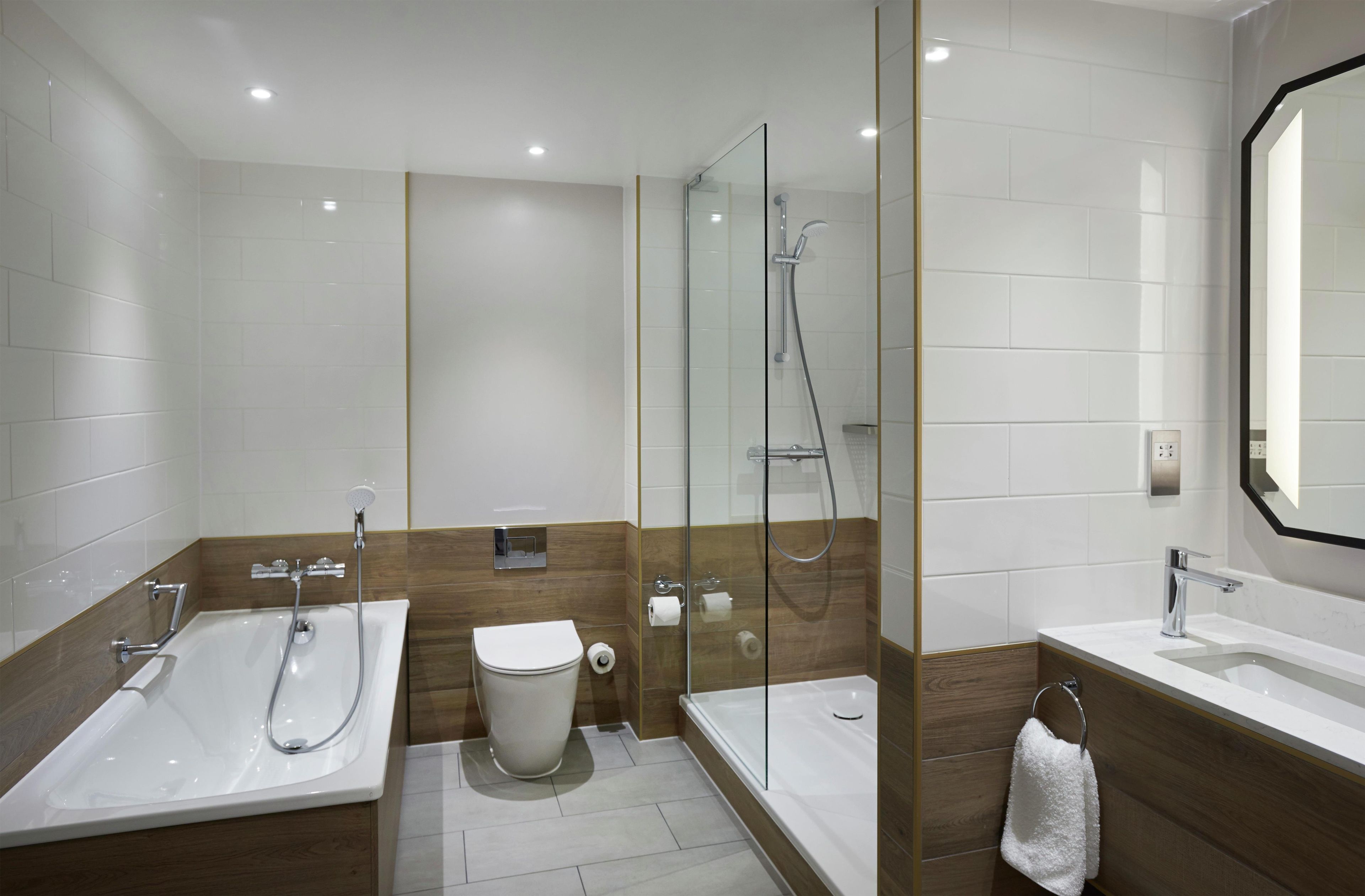 A modern bathroom with a glass-enclosed shower, a bathtub, and a sink.