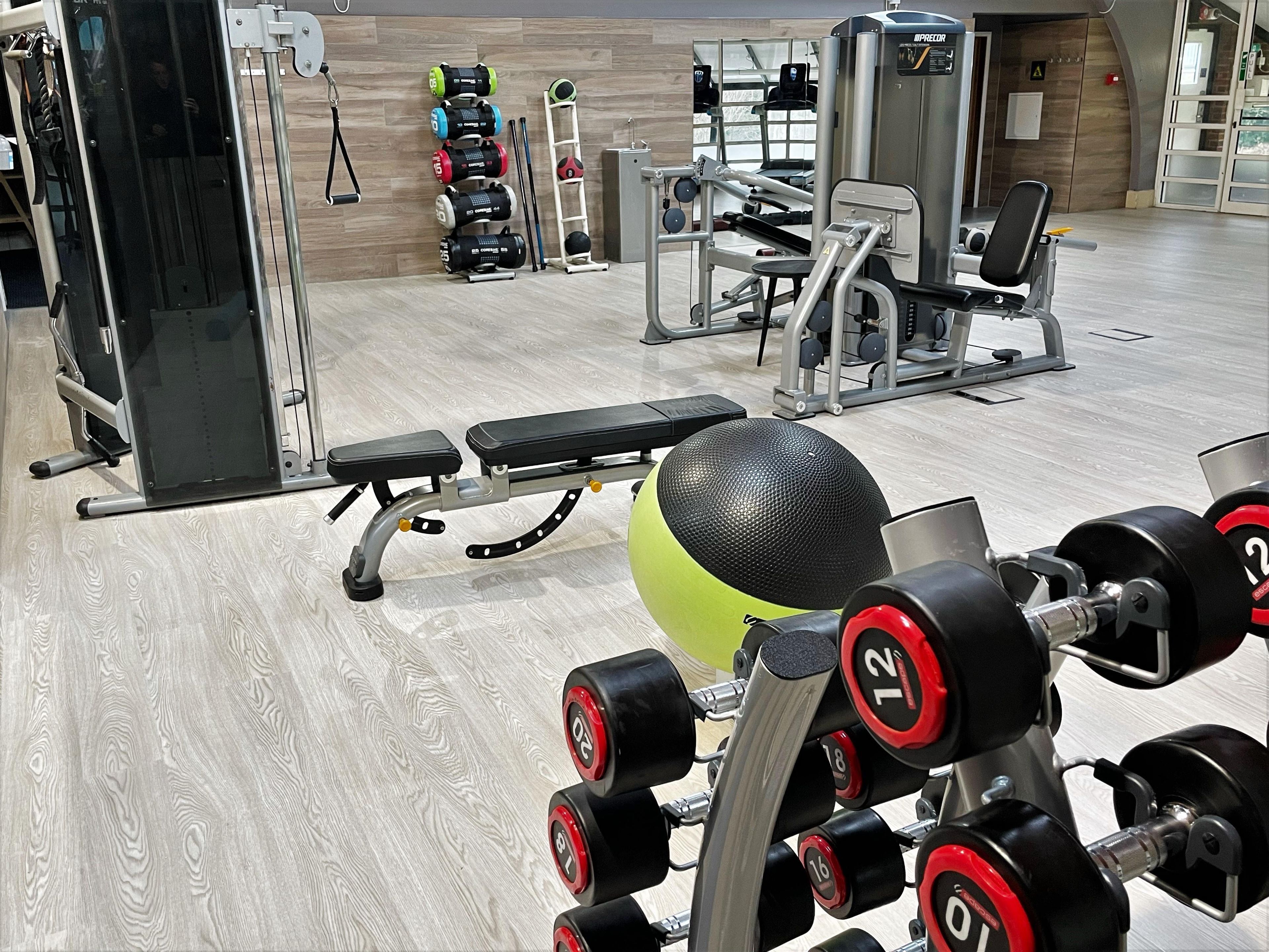 Ein Fitnessstudio mit Gewichthebern, Bänken und Trainingsgeräten.
