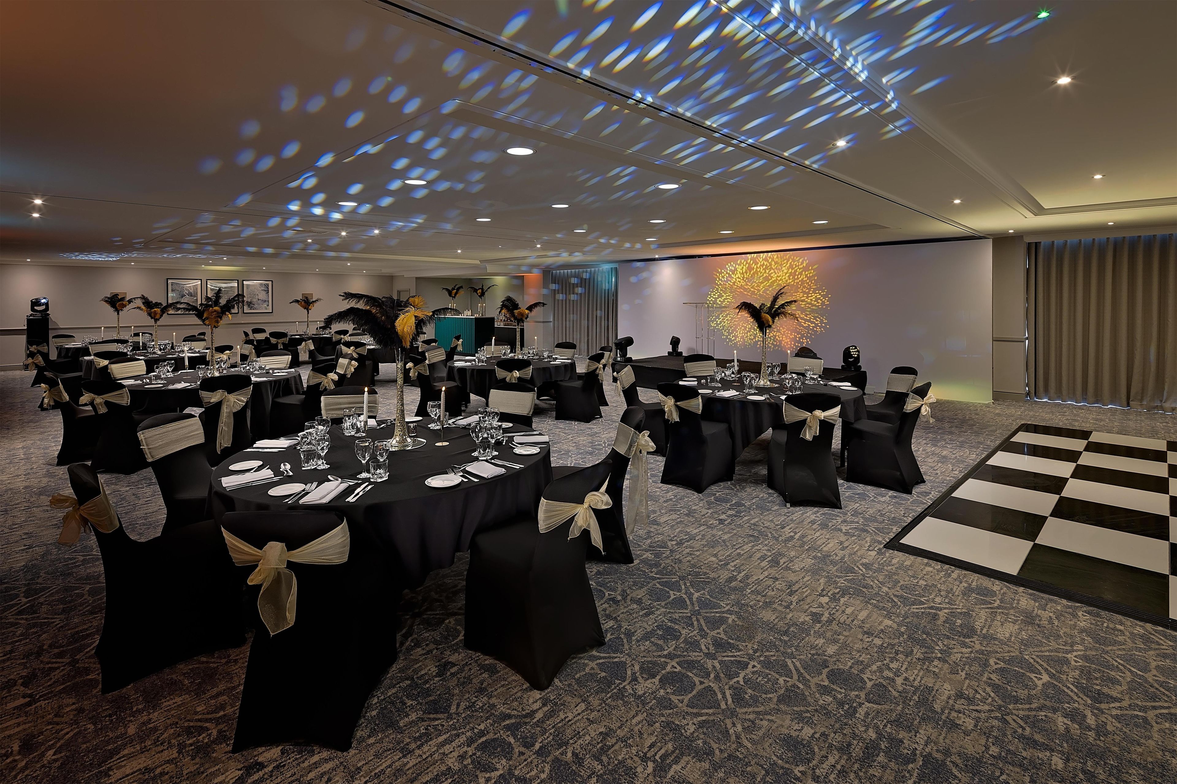 A conference room with round tables, black chairs, and a checkered floor.