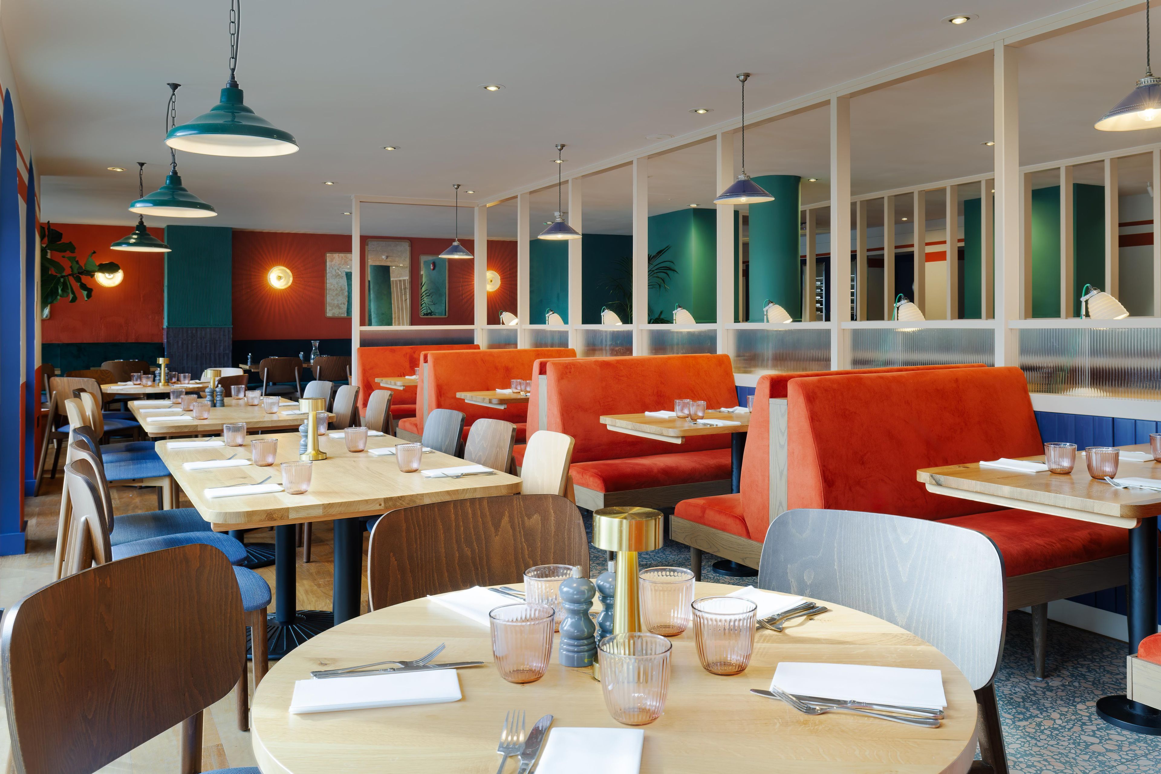 A restaurant with multiple tables and booths, some with orange seating.