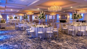 A banquet hall with round tables, white chairs, and chandeliers. - DoubleTree by Hilton Tinton Falls - Eatontown (Tinton Falls)