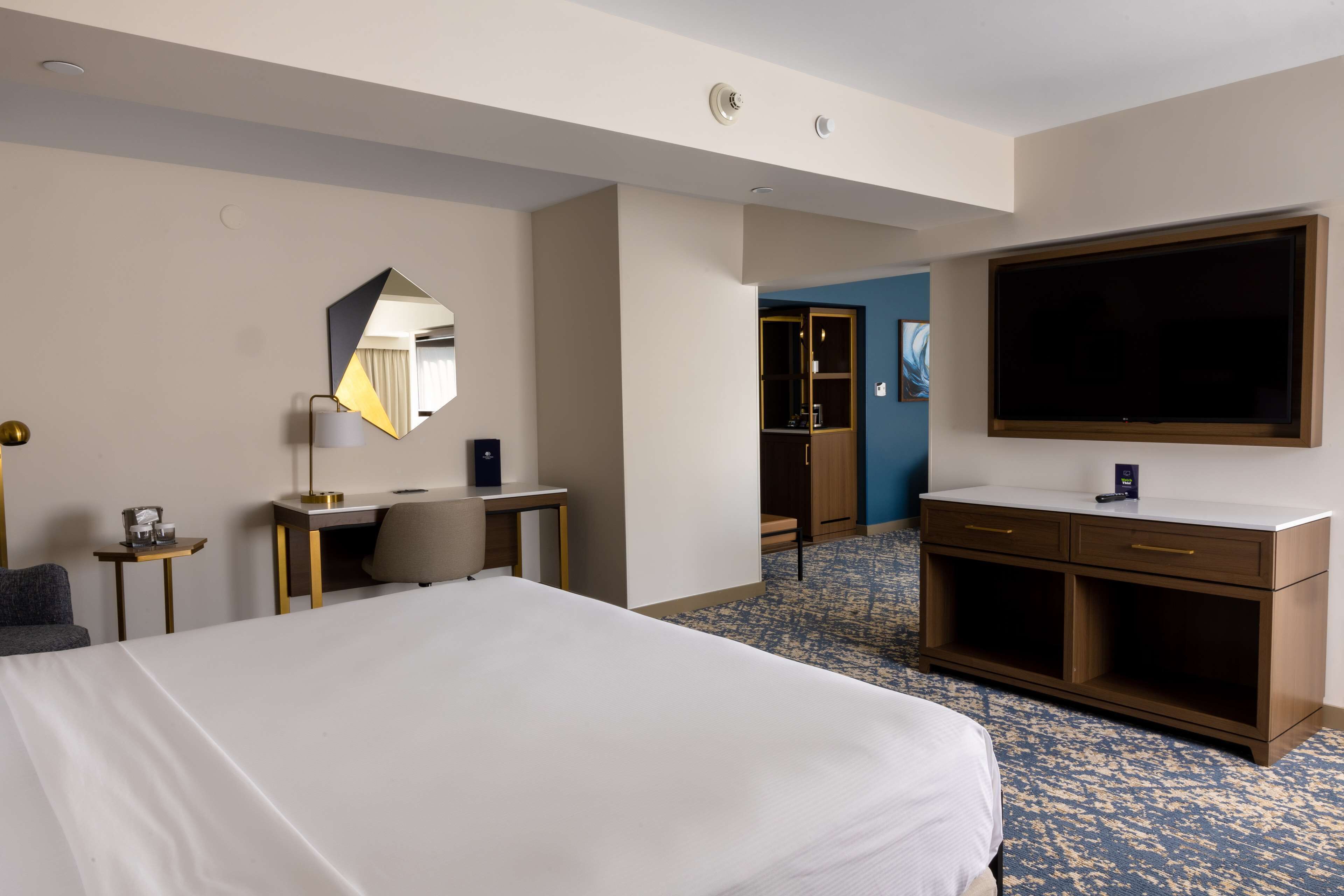 Una habitación de hotel con una cama grande, un escritorio, una silla, un televisor y un armario.