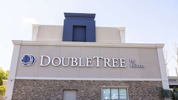 La façade d’un hôtel DoubleTree by Hilton, avec une enseigne bien visible, des éléments en briques et une fenêtre.