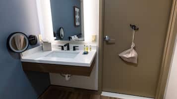 A bathroom with a large sink, mirror, towel rack, and a door with a towel hanging on it.