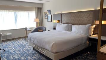 Una habitación de hotel con una cama grande, un escritorio, una silla y una ventana con cortinas.