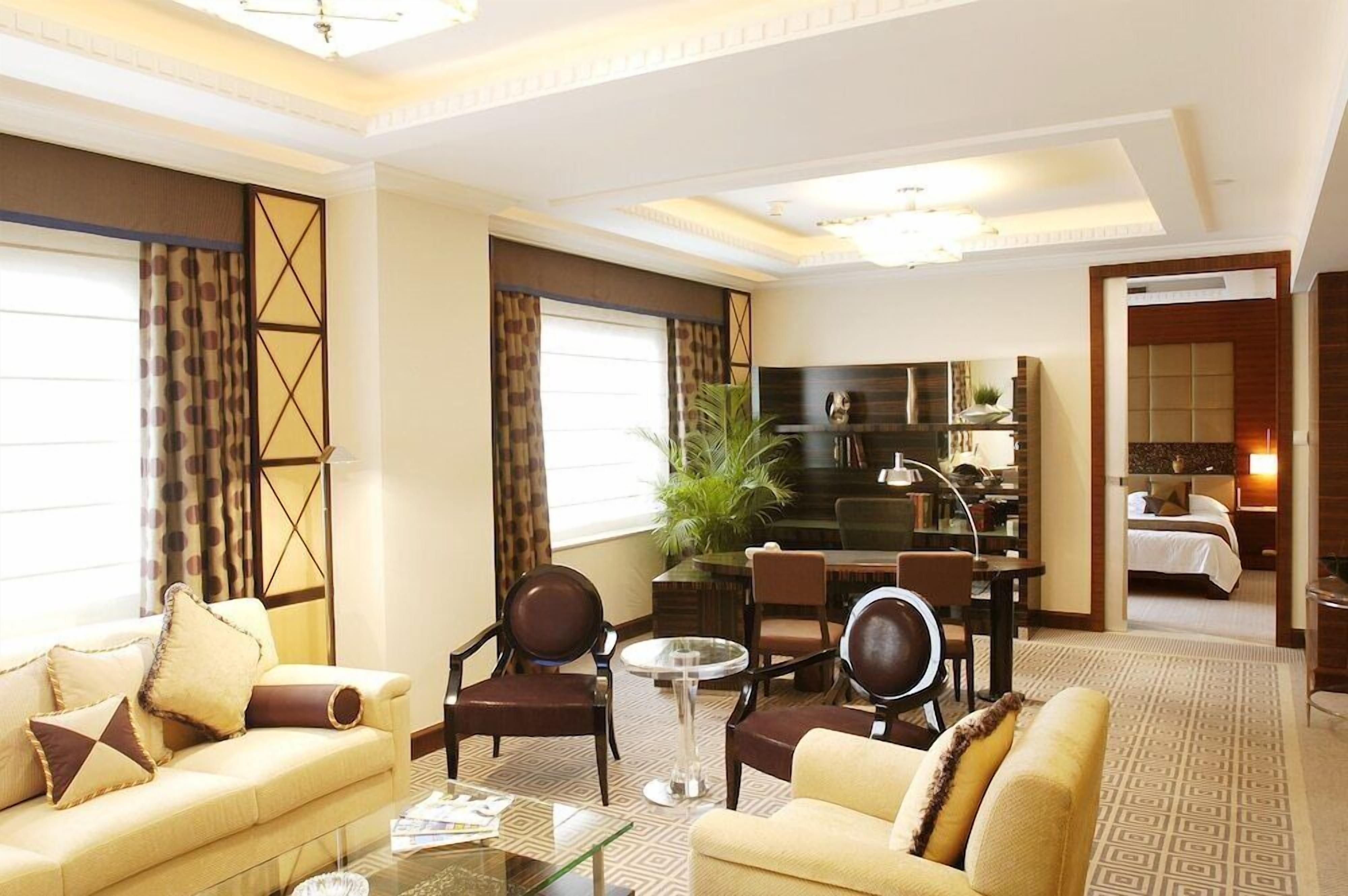 A hotel room with a living area, dining space, and a separate bedroom.