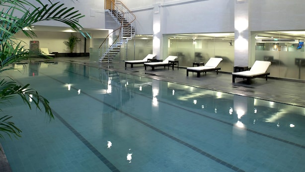 An indoor swimming pool with clear water, a glass ceiling, and lounge chairs along the poolside. - Hotel New Otani Chang Fu Gong (Beijing)