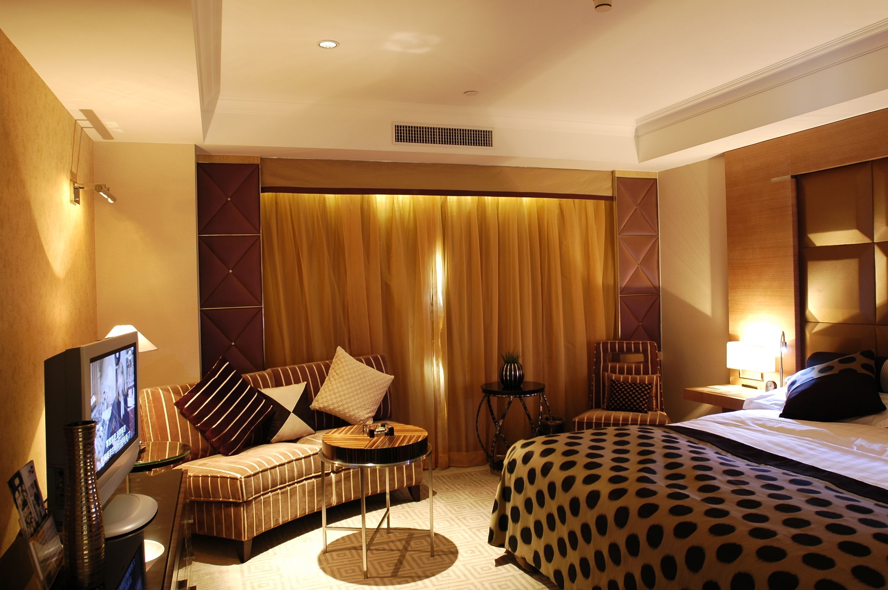 A hotel room with a bed, a sofa, a TV, and a small table.
