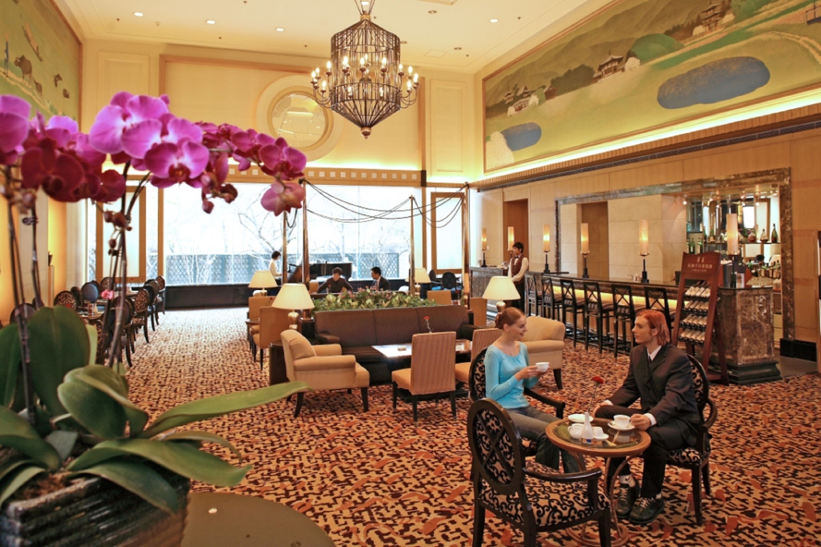 A lobby with a patterned carpet, a reception desk, and a chandelier.