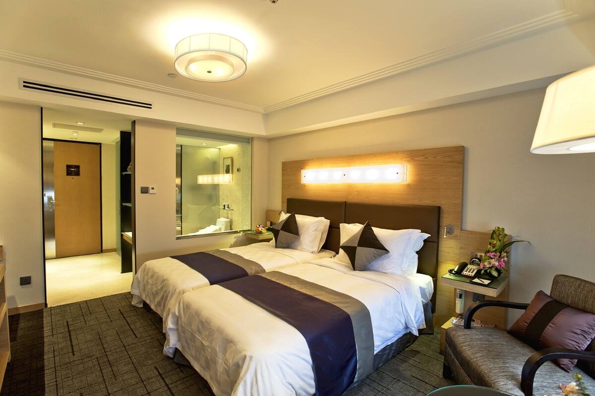 A hotel room with a large bed, a desk with a telephone, and a mirror.