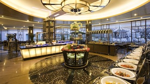 A buffet area with a central island, multiple serving stations, and a large window providing a view of the outside. - Hotel New Otani Chang Fu Gong (Beijing)