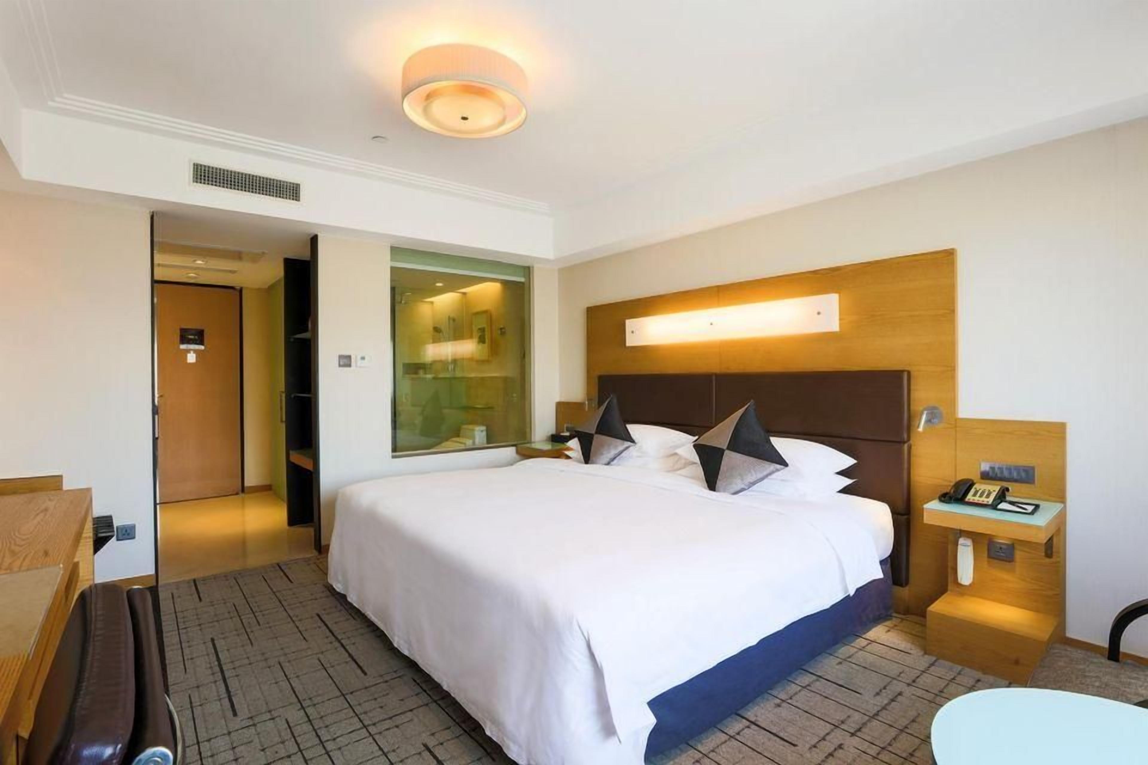 Una habitación de hotel con una cama grande, una mesita de noche y un pequeño escritorio con una silla.